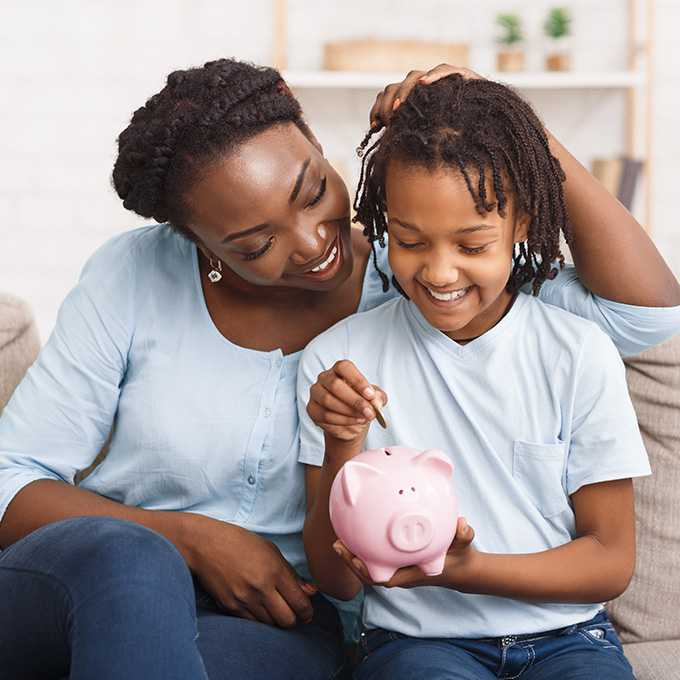 Mutter mit Kind stecken eine Münze in das Sparschwein